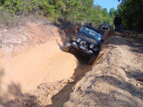 2004 Jeep Wrangler - 2004 Jeep TJ tackling a challenging off-road trail with steep inclines and sandy terrain.
