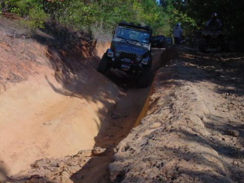 2004 Jeep Wrangler - A black Jeep TJ navigates a challenging sandy off-road trail with other vehicles visible in the background.
