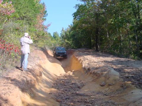 2004 Jeep Wrangler - A Jeep Wrangler navigates a challenging off-road trail with a photographer observing from the side.