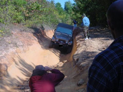 2004 Jeep Wrangler - A Jeep Wrangler TJ navigates a challenging off-road trail with onlookers observing the action.