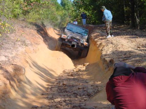 2004 Jeep Wrangler - A Jeep Wrangler TJ tackles a challenging off-road course, demonstrating its capability on rough terrain.