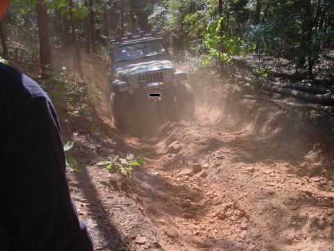 2004 Jeep Wrangler - A Jeep Wrangler TJ navigates a challenging dirt path through a wooded area.
