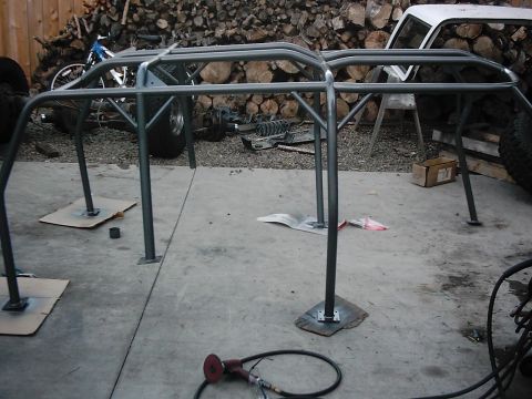 1978 Ford Bronco - Roll cage assembly being worked on, with parts and a vehicle in the background.