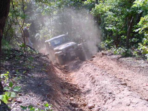 2004 Jeep Wrangler - Jeep TJ navigates a challenging off-road course, kicking up a cloud of dust.