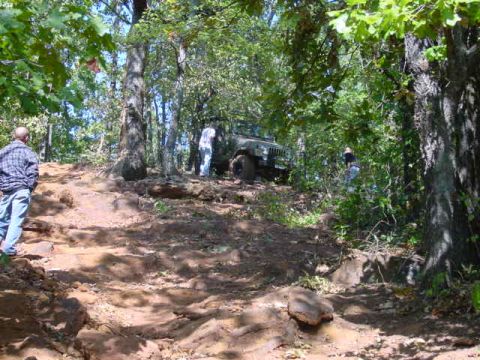 2004 Jeep Wrangler - A 2004 Jeep TJ navigates a challenging off-road trail through a forest.