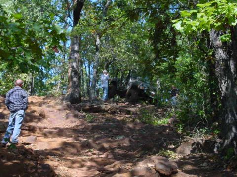 2004 Jeep Wrangler - A Jeep navigates a challenging off-road path through a dense forest with onlookers present.