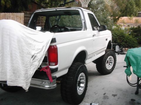 1978 Ford Bronco - This white Ford Bronco, viewed from the rear quarter, has a lifted suspension and oversized tires, suggesting a later model year.