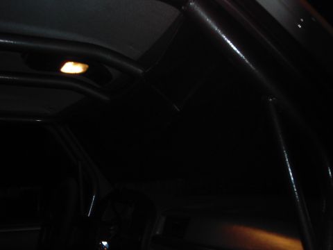 1978 Ford Bronco - The interior of a vehicle is visible, a black roll cage and an illuminated dome light.