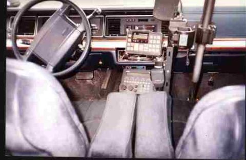 1991 Ford LTD Crown Victoria - Front interior of a sedan with bench-style seats and a console-mounted radio and control head between the seats.