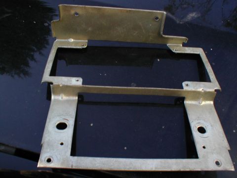 1979 Ford Bronco - A metal bracket with mounting holes and tabs is shown, likely a component for a vehicle's interior.