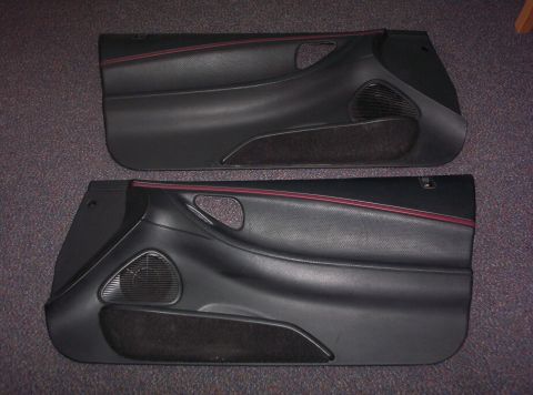 1994 Ford Probe - A pair of black interior door panels with red accent trim are displayed on a carpeted surface.
