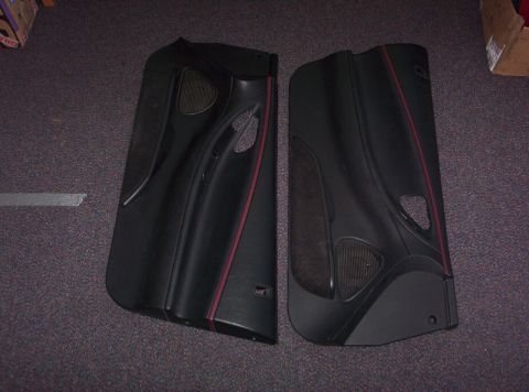 1994 Ford Probe - A pair of black interior door panels with red accent trim are displayed on a carpeted surface.