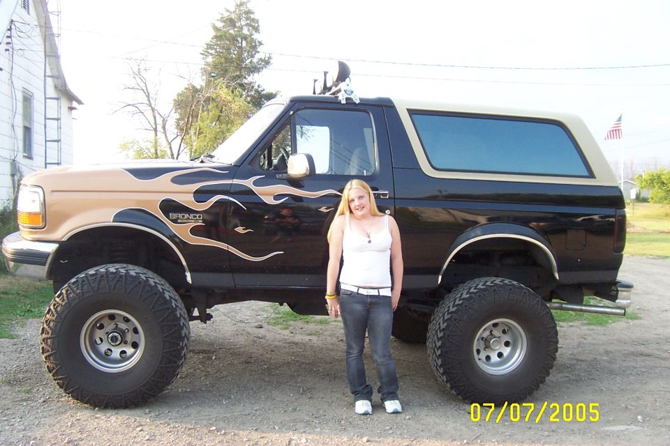 Black and tan lifted Ford Bronco with flame decals and large tires
