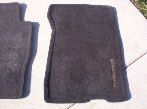 1994 Ford Probe - Two dark gray car floor mats are shown, one with faint embossed text on the right side.