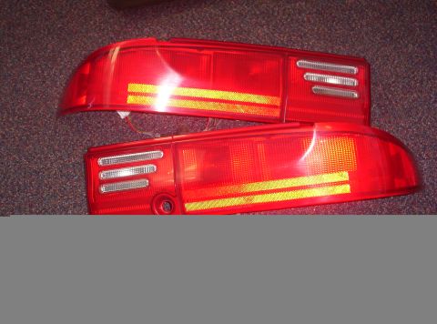 1994 Ford Probe - A pair of red automotive taillights are displayed against a dark, textured background.