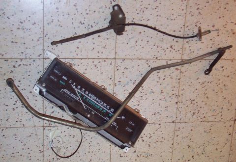 1985 Ford LTD Crown Victoria - Various automotive parts, including a speedometer and linkage components, are laid out on a tiled surface.