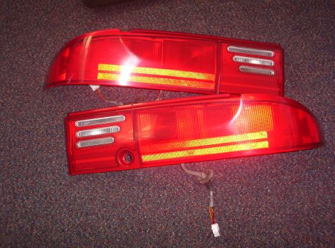 1994 Ford Probe - Two red tail lights, likely for a car, are shown on a carpeted surface.