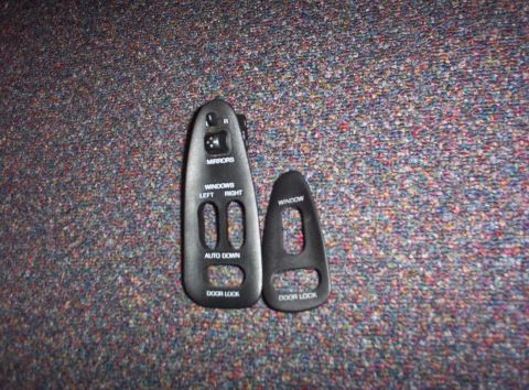 1994 Ford Probe - Two interior trim pieces for car door controls, including window and door lock switch bezels, are shown against a carpeted background.