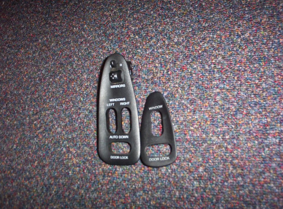 Two black plastic bezels for car door controls, one with mirror and window switches, the other with just window and door lock buttons