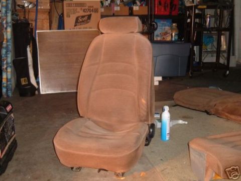 1991 Ford Bronco - Several vehicle seats are disassembled and stored in a cluttered garage environment.