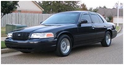 1999 Ford Crown Victoria - Black Ford Crown Victoria sedan parked on a street, front 3/4 view.
