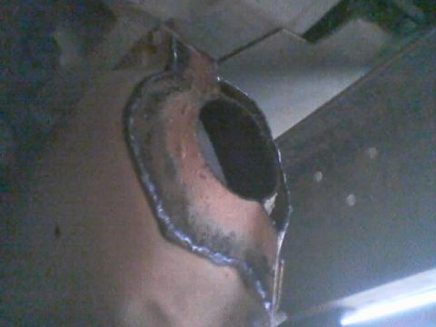 1990 Ford Bronco - Close-up of a freshly welded steel bracket showing rough weld beads around an open oval hole on a fabricated mount.