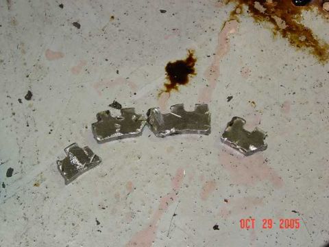 2003 Dodge 1500 - Engine bearing fragments on a dirty surface with a date stamp from 2005.