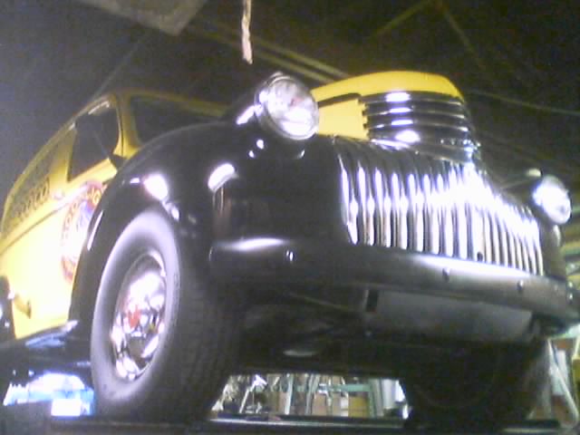 Front view of a black truck grille and headlight next to a yellow panel van