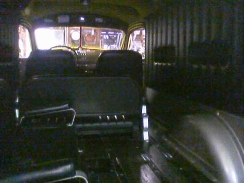 1968 Ford Mustang - The interior of a van is visible, showing dark seats and ribbed paneling along the sides.