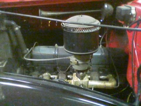 1968 Ford Mustang - The engine compartment of a vehicle, showing the air filter assembly and carburetor.