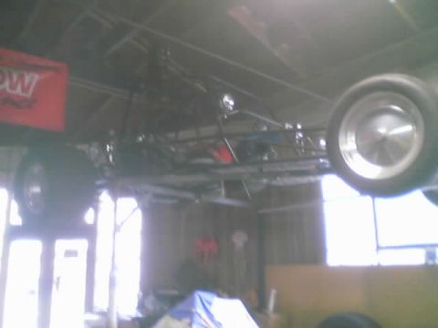1968 Ford Mustang - Sand rail chassis suspended from ceiling in a workshop. A red banner hangs on the wall.