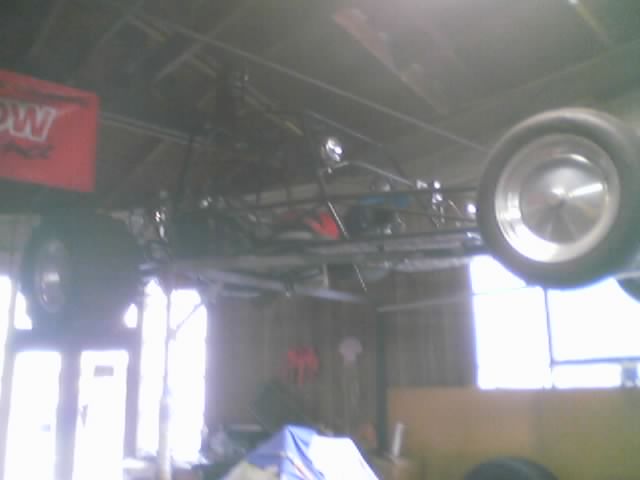 Sand rail chassis with wheels, suspended from ceiling. Red banner with white text visible