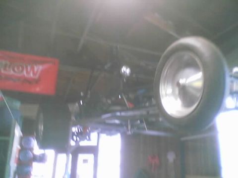 1968 Ford Mustang - The underside of a go-kart chassis is visible, with its large rear wheels prominently displayed.