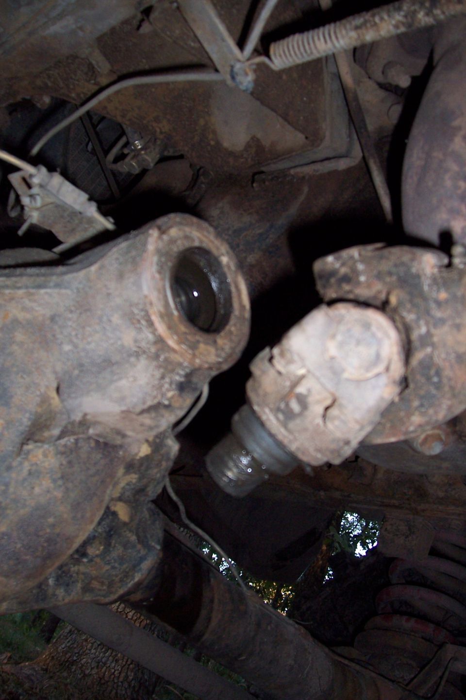 Undercarriage of a rusty vehicle showing a ball joint and suspension components