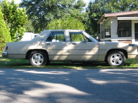1985 Ford Crown Victoria LTD - Side view of a beige 1985 Ford Crown Victoria LTD sedan.