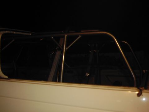 1978 Ford Bronco - A white vehicle's interior is visible, a prominent roll cage structure.