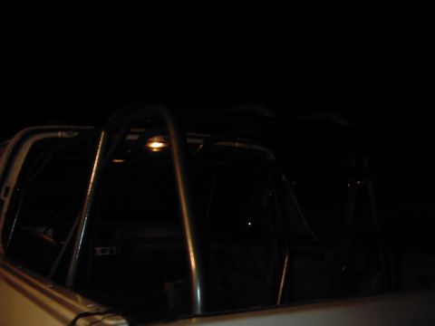 1978 Ford Bronco - A roll cage is installed inside a vehicle, illuminated by a single interior light.