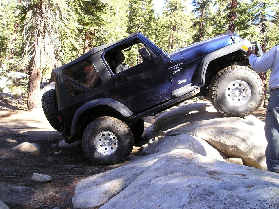 Dark blue Jeep Wrangler TJ off-roading over rocks