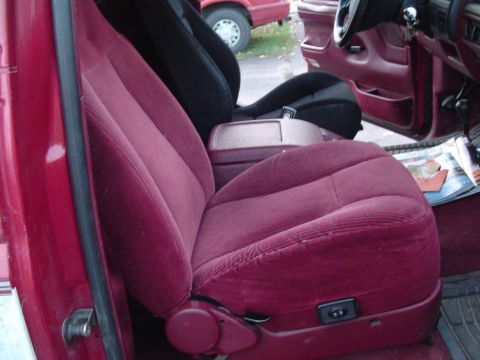 1994 Ford Bronco - Interior view of a red vehicle, maroon corduroy seats and a glimpse of another vehicle outside.