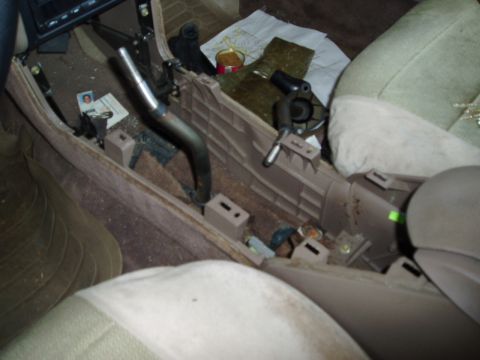 1995 Ford Taurus - The interior of a car shows a disassembled center console with a shifter and various items scattered around.
