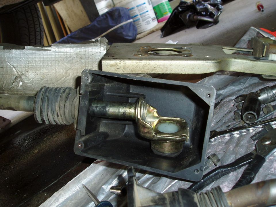 Disassembled wiper motor linkage showing gold crank arm and white nylon bushing