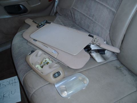 1995 Ford Taurus - Disassembled interior parts, including a sun visor and dome light, are placed on a car seat.