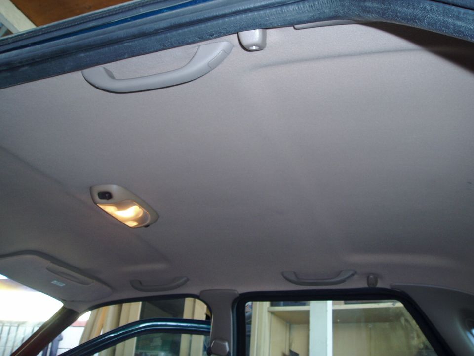 Gray vehicle headliner interior with overhead grab handles and dome light