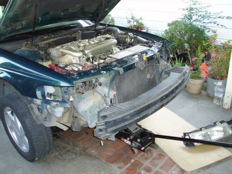 1995 Ford Taurus - Front end of a 1995 Ford Taurus undergoing repairs, with the bumper detached and engine visible.
