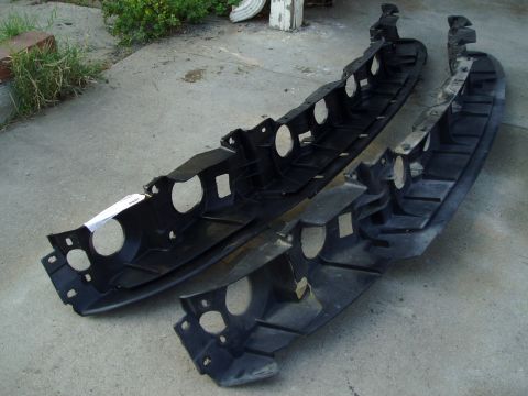 1995 Ford Taurus - Two black plastic bumper reinforcement beams are shown on a concrete surface.
