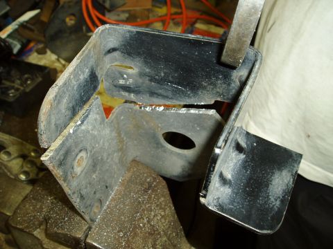 1995 Ford Taurus - A damaged black metal bracket is clamped in a vise, showing signs of stress and breakage.