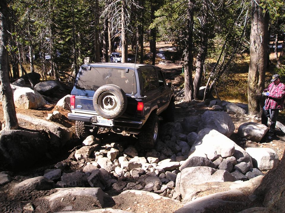 Dark blue SUV on a rocky trail, spare tire on rear door, license plate visible