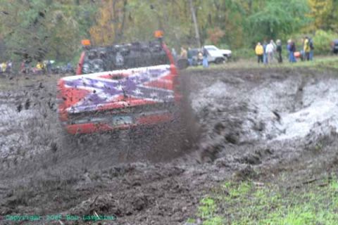 1976 GMC C/K Pickup - A 1976 GMC C/K Pickup is stuck in a mud pit, with spectators in the background.