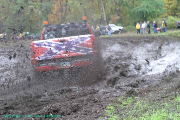 1976 GMC C/K Pickup stuck in mud, red and purple flag design on bed, orange hazard light on roof
