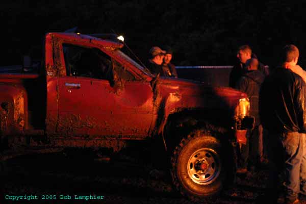 Mud-covered red pickup truck, driver's side view